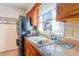 This kitchen boasts wooden cabinets, a stainless steel refrigerator, and a double basin sink under a bright window at 317 14Th Ave. N, Surfside Beach, SC 29575