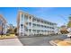 Three-story condo building with pale blue siding, white stairs and railings, and stone accents under a bright blue sky at 4655 Wild Iris Dr. # 101, Myrtle Beach, SC 29577