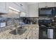 Close-up of the well-equipped kitchen featuring granite counters, stainless sink and black appliances at 5511 North Ocean Blvd. # 1105, Myrtle Beach, SC 29577