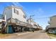 Street view of the elevated beach house with other beach houses along the street at 6001 -1005 S Kings Hwy., Myrtle Beach, SC 29575