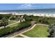 Beautiful view of the beach from the property's balcony overlooking a manicured lawn and coastal landscape at 645 Retreat Beach Circle, Pawleys Island, SC 29585