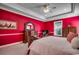 Spacious main bedroom featuring bold red walls, plush carpeting, and decorative tray ceiling with fan at 702 Compass Point Dr., North Myrtle Beach, SC 29582