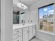 Well-lit bathroom with a white vanity, decorative mirror, and a window offering a view at 7228 Guinevere Circle, Myrtle Beach, SC 29588