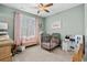 Cozy bedroom with pastel green walls, pink curtains, crib, play kitchen, and bench seat at 900 Berwick Ln., Myrtle Beach, SC 29579