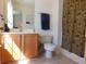 Well-lit bathroom features a wood vanity, toilet, mirror, and a shower with a decorative curtain at 1027 Pinwheel Loop # 3103, Myrtle Beach, SC 29577