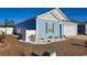 A blue single-story home with a well-manicured lawn, gravel accents with a two-car garage at 127 Clover Walk Dr., Conway, SC 29526