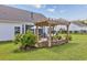 Backyard view with a pergola-covered outdoor kitchen area, dining area, and lush landscaping at 172 Board Landing Circle, Conway, SC 29526