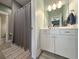 Bright bathroom features a shower with a gray curtain, white cabinets with marble countertop and stylish decor at 202 Spreading Oak Dr., Pawleys Island, SC 29585