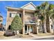 Brick condo building with mature landscaping including a palm tree near the front entrance at 210 Double Eagle Dr. # G1, Myrtle Beach, SC 29575