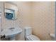 A half-bathroom has a pedestal sink and a toilet, and is wallpapered with a lovely pattern at 321 Jay St., Murrells Inlet, SC 29576