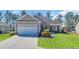 Charming single-Gathering home featuring a two-car garage, stone accents, and well-manicured lawn at 556 Timber Creek Dr., Loris, SC 29569
