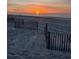 Tranquil beach scene featuring wooden fence posts and a captivating sunset, perfect for relaxation and scenic views at 5601 N Ocean Blvd. # E-111, Myrtle Beach, SC 29577