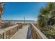 Elevated boardwalk leads to a sandy beach and ocean view, framed by lush palms at 6803 Ocean Blvd. N # 109, Myrtle Beach, SC 29572