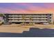 Four-story condo building featuring gray siding, balconies with white railings and a ground level parking area, and a colorful sunset at 123 Dogwood Dr. N # 205-A, Murrells Inlet, SC 29576