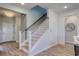 Staircase has wood treads and handrail, white risers and spindles with a view of the front door at 1275 Winding Creek Way, Myrtle Beach, SC 29588