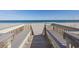 A wooden walkway leads to a pristine beach with clear blue ocean waters at 1581 South Waccamaw Dr. # 304, Garden City Beach, SC 29576