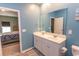 Bathroom featuring a double sink vanity and a view into the adjacent bedroom with a gray and blue bedspread at 184 Carolina Lakes Blvd., Myrtle Beach, SC 29588