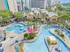 Aerial view of a lazy river and pool area with palm trees, lounge chairs, and colorful umbrellas at 205 74Th Ave. N # 1508, Myrtle Beach, SC 29572