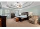 This main bedroom features a tray ceiling, ceiling fan, wood furniture and a sitting area with recliner at 2350 Clandon Dr., Myrtle Beach, SC 29579