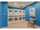 A bright laundry room with blue walls, multiple machines, and a folding area at 2401 S Ocean Blvd. # 1260, Myrtle Beach, SC 29577