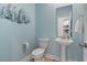 Stylish powder room with blue walls, pedestal sink, toilet, and sailboat wall decor at 2476 Blue Crane Circle # 101, Myrtle Beach, SC 29577