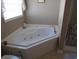 Bright bathroom showcasing a corner jacuzzi tub beneath a window, perfect for relaxation and spa days at 3158 River Bluff Ln., Little River, SC 29566