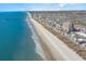 Beachfront view from above shows wide sandy beach, buildings, and ocean with pier at 4103 N Ocean Blvd. # 207, North Myrtle Beach, SC 29582