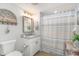 Cozy bathroom with decorative shelf, updated vanity, framed mirror, and shower with striped curtain at 4103 N Ocean Blvd. # 207, North Myrtle Beach, SC 29582