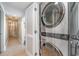 Hallway view of modern stacked washer and dryer with white louvered door and tile floors at 4103 N Ocean Blvd. # 207, North Myrtle Beach, SC 29582