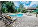 Relaxing community pool area with lounge chairs, mature trees, and a glimpse of nearby buildings at 415 Ocean Creek Dr. # 2202, Myrtle Beach, SC 29572