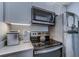 Kitchenette featuring stainless steel appliances, modern cabinets, and a sleek black cooktop and microwave setup at 415 Ocean Creek Dr. # 2202, Myrtle Beach, SC 29572