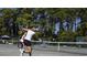 Active tennis court scene, showcasing a player in motion with lush greenery in the background at 415 Ocean Creek Dr. # 2202, Myrtle Beach, SC 29572