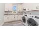 Bright laundry room featuring built-in cabinets, granite countertops, a utility sink, and modern washer and dryer units at 1042 Muscovy Pl., Conway, SC 29526