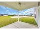 Covered back patio with a ceiling fan, providing a tranquil outdoor space overlooking a green yard and pond at 1064 Jase Dr., Longs, SC 29568
