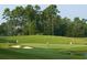 Scenic view of a lush golf course with golfers, sand traps, and towering trees in the background at 1064 Jase Dr., Longs, SC 29568