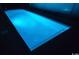 Illuminated rectangular pool surrounded by a dark deck. The pool features built in lighting at 140 Northside Dr., Little River, SC 29566