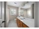 Bright bathroom features a white vanity with wood cabinets, white tile floors, and a window for natural light at 172 Hawthorn Dr., Pawleys Island, SC 29585