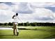 Scenic golf course view with a golfer swinging against a backdrop of green trees and blue skies at 2017 Lone Cypress Dr, Myrtle Beach, SC 29579