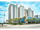 Attractive exterior view of a resort with palm trees, blue awnings and ocean glimpses at 2401 S Ocean Blvd. # 953, Myrtle Beach, SC 29577