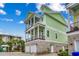 Green three-story home with multi-level balconies, a brick facade, and a two-car garage at 316 Shuffleboard Ct., Myrtle Beach, SC 29572