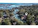 A scenic aerial view captures a lovely waterway home with a red roof amid a lush landscape and tranquil waters at 3615 Sunfish St., Murrells Inlet, SC 29576