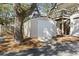 A white storage shed sits near a home's elevated deck, nestled under a tree with pine straw bedding at 3615 Sunfish St., Murrells Inlet, SC 29576