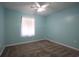 Blue bedroom with carpeted floors, a ceiling fan, and a window with white curtains allowing soft, natural light at 4339 Dew N. Ct., Myrtle Beach, SC 29579