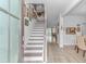 Bright foyer with staircase, light hardwood floors, and gallery wall of framed art leading to dining and living areas at 560 Pier Ct., Longs, SC 29568