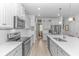 Bright kitchen featuring white cabinets, stainless steel appliances, quartz countertops, and a view of the dining area at 560 Pier Ct., Longs, SC 29568