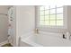 Bright bathroom featuring a soaking tub with a floral shower curtain and a large window at 825 Payne Ct., Conway, SC 29526