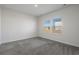 Neutral bedroom featuring plush carpet, white walls, and double windows for natural light at 8500 Dunes Point Way, Longs, SC 29568