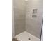 Modern bathroom showing shower with neutral colored tile and built-in shelving niche at 969 Oak Hollow St., Longs, SC 29568