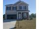 Two-story home with stone accents, an attached garage, and manicured lawn at 990 Oak Hollow St., Longs, SC 29568