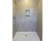 Neutral-toned tiled shower stall with built in storage niches and a white shower pan at 990 Oak Hollow St., Longs, SC 29568